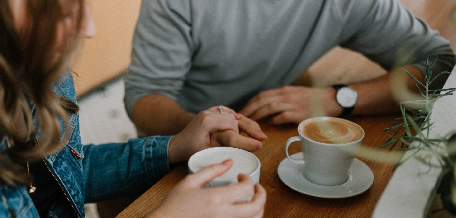 Man and woman having a coffee holding hands for support